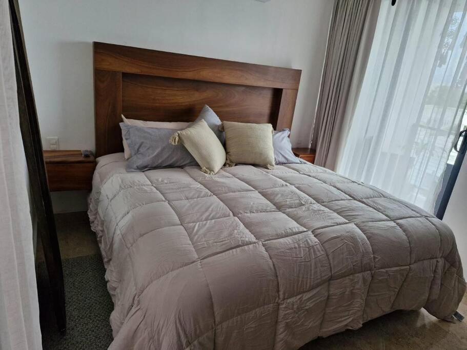 a bedroom with a large bed with a wooden headboard at Penthouse cerca de la playa in Tulum