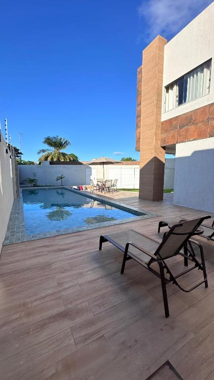 a patio with a bench and a swimming pool at Mansão Moraes - em Itacimirim Linha Verde in Camacari
