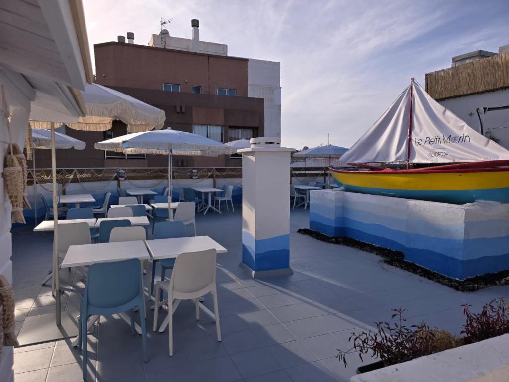 a boat sitting on a roof with tables and chairs at Ura Hotel Boutique Gurea in Las Palmas de Gran Canaria