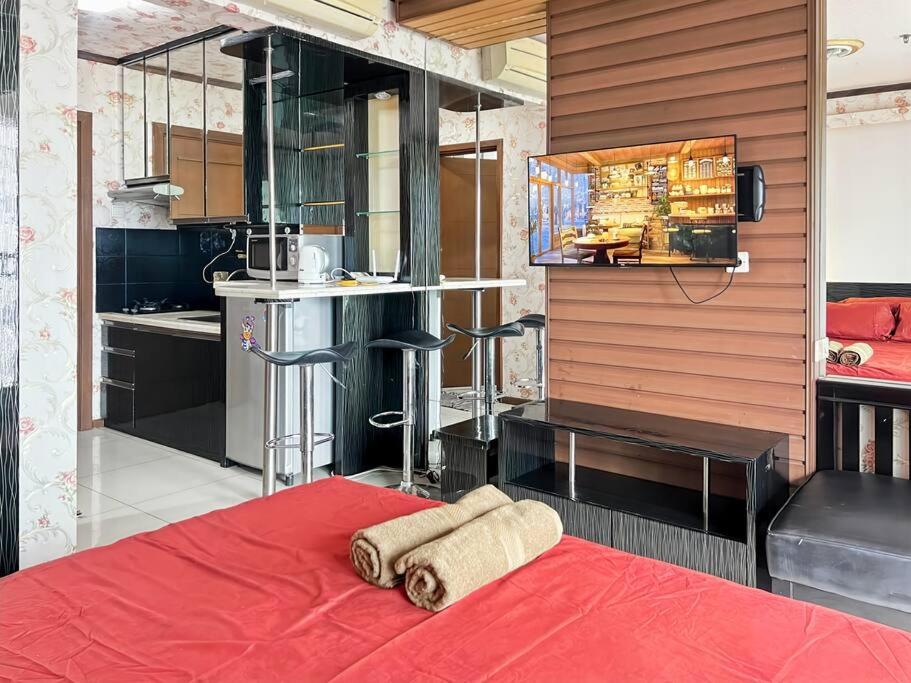 ジャカルタにあるStrategic Thamrin Executive Apt with Pool & Gym by 2ndHomeのベッドルーム1室(赤いベッド1台付)、キッチンが備わります。
