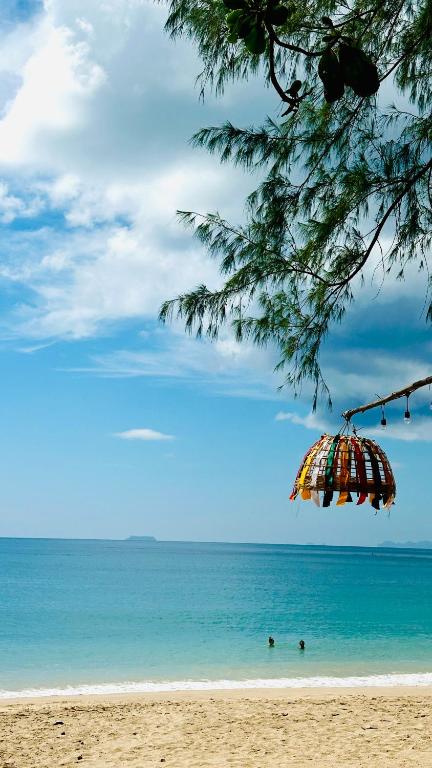 an umbrella on a beach with people in the water at Lanta L.D. Beach Bungalow in Ko Lanta