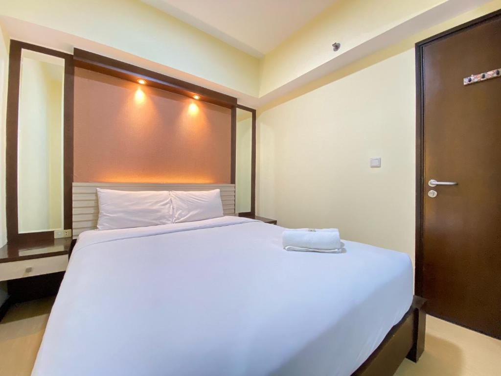 a bedroom with a large white bed with a wooden headboard at Spacious and Modern 2BR at Braga City Walk Apartment By Travelio in Bandung