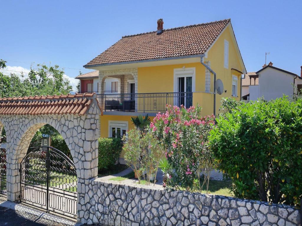 a yellow house with a gate and a stone fence at Holiday home in center of ilo near beach in Šilo