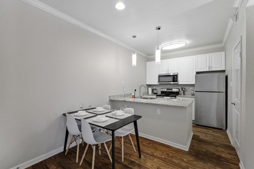 eine weiße Küche mit einem schwarzen Tisch und Stühlen in der Unterkunft Chic 1BD Retreat With Pool & Gym, Heart of Medical City Plano in Plano
