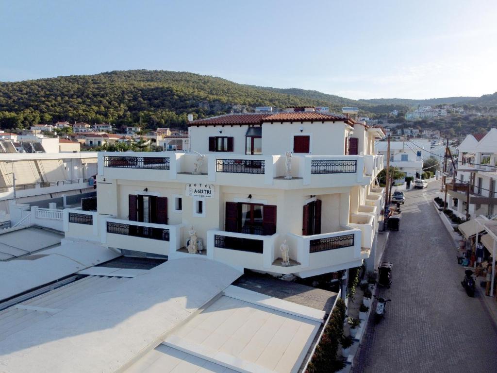 a large white building with balconies on a street at Agistri Hotel in Skala