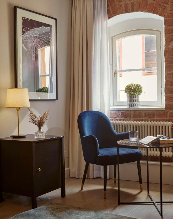 a living room with a blue chair and a window at Hôtel Reisen in The Unbound Collection by Hyatt in Stockholm