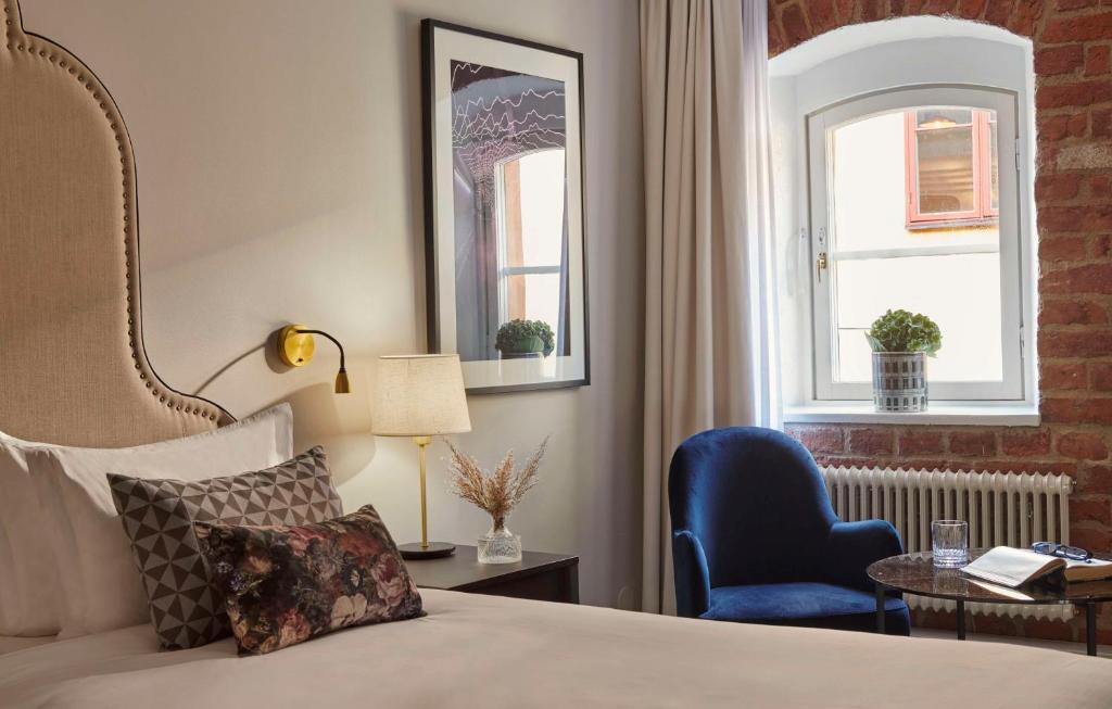 a bedroom with a bed and a chair and a window at Hôtel Reisen in The Unbound Collection by Hyatt in Stockholm