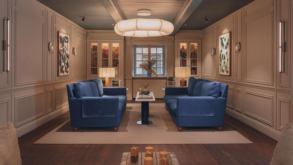 a living room with two blue chairs and a table at Hôtel Reisen in The Unbound Collection by Hyatt in Stockholm