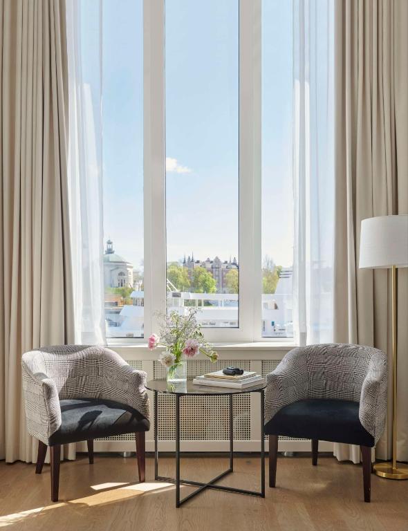 a living room with two chairs and a table and windows at Hôtel Reisen in The Unbound Collection by Hyatt in Stockholm