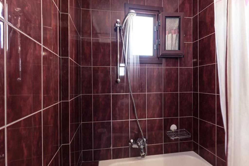a bathroom with a shower and a bath tub at Agistri Hotel in Skala