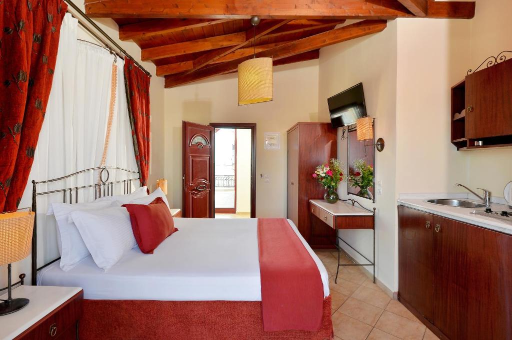 a bedroom with a large white bed and a kitchen at Agistri Hotel in Skala