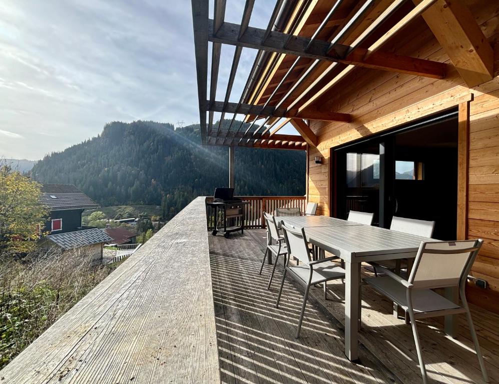 une terrasse en bois avec une table et des chaises dessus dans l'établissement Chalet des Freinets : proche centre de Châtel et au calme, à Châtel