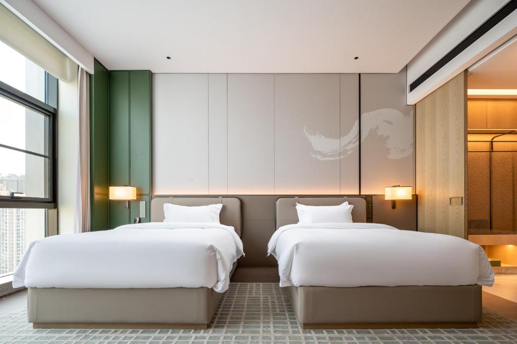 two beds in a hotel room with white sheets at Qinglian Jinghe Hotel Wuhan Zoo International Expo Center Branch in Han-yang-hsien