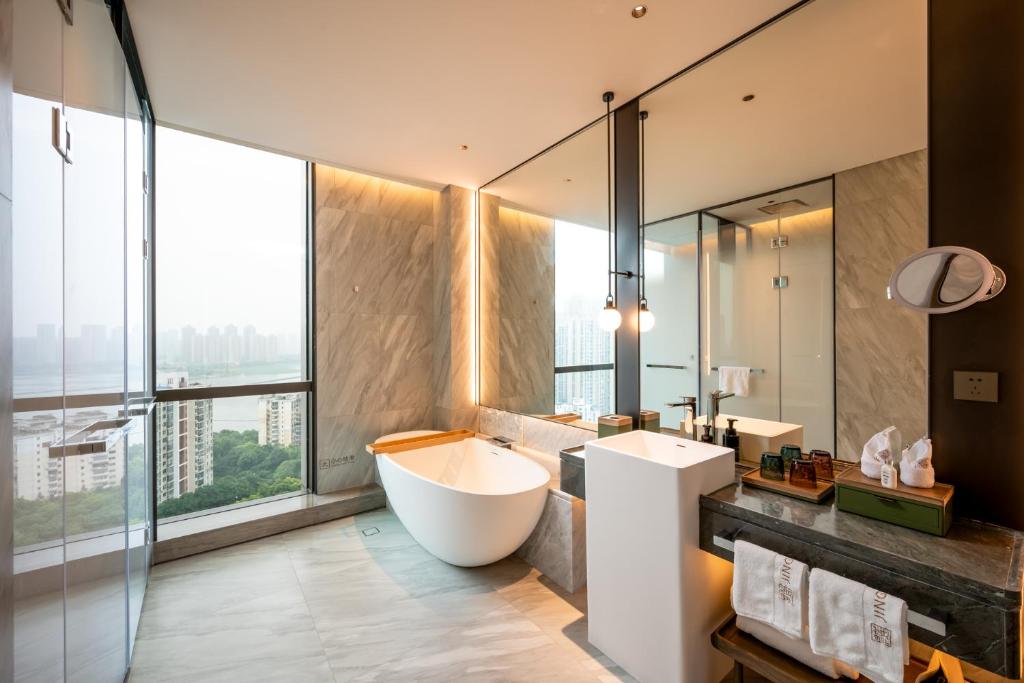 a bathroom with a tub and a large window at Qinglian Jinghe Hotel Wuhan Zoo International Expo Center Branch in Han-yang-hsien