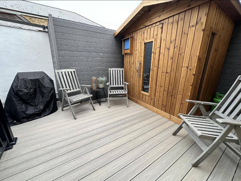 zwei Stühle auf einem Holzdeck mit einem Gebäude in der Unterkunft Central Margate house with sauna & private garden in Kent