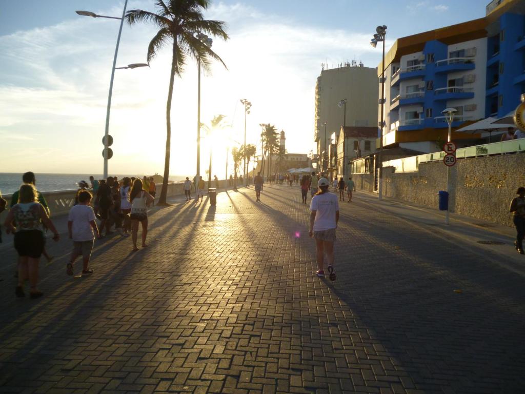 a group of people walking down a sidewalk near the beach at Flat no Farol in Salvador