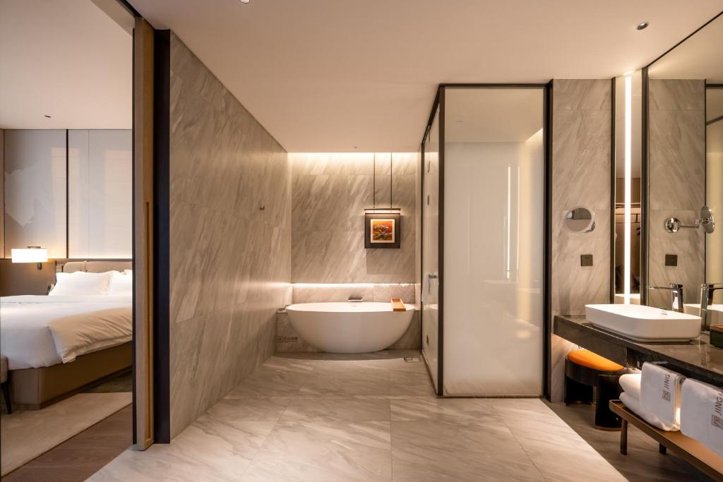 a bathroom with a sink and a tub and a bed at Qinglian Jinghe Hotel Wuhan Zoo International Expo Center Branch in Han-yang-hsien