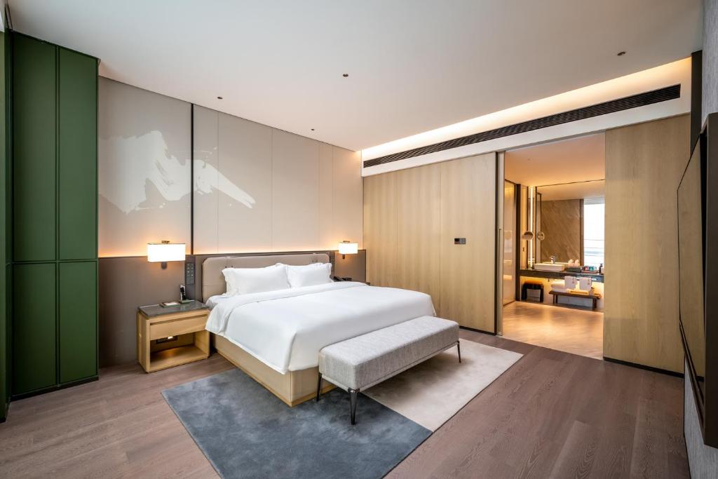 a bedroom with a white bed and a green wall at Qinglian Jinghe Hotel Wuhan Zoo International Expo Center Branch in Han-yang-hsien