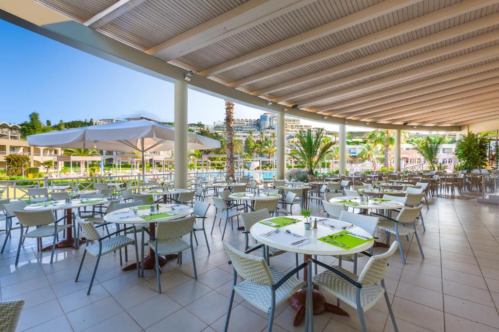 restauracja z białymi stołami i krzesłami na patio w obiekcie Kipriotis Maris Suites w mieście Kos