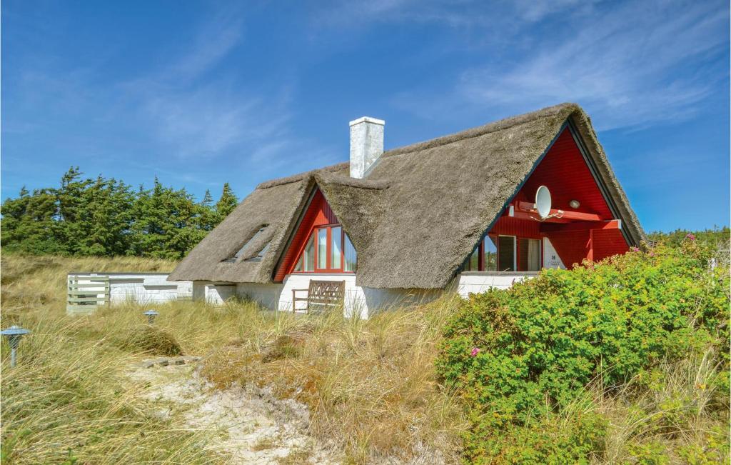 a red and white house with a thatched roof at Holiday Home Tingodden Iv in Hvide Sande