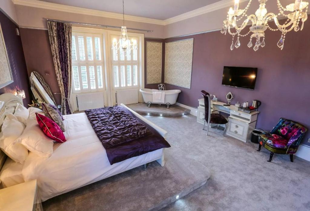 a large bedroom with a large bed and a tub at Derby Manor in Bournemouth