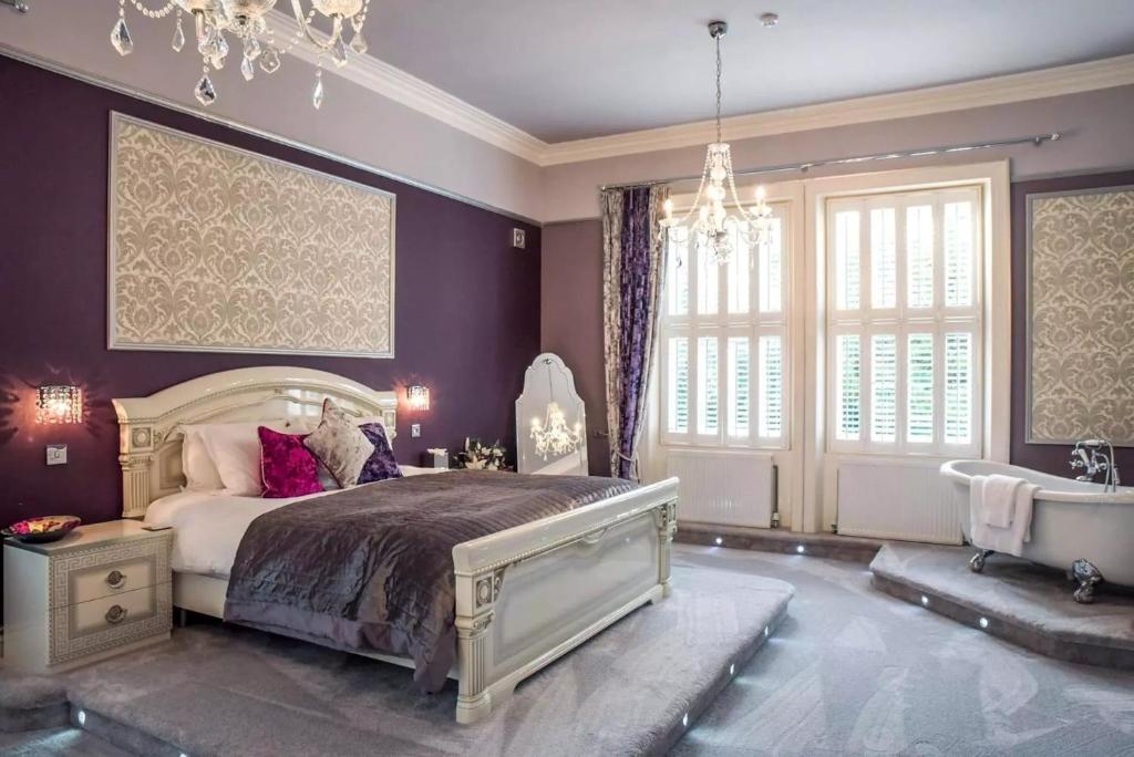 a bedroom with a bed and a tub and a chandelier at Derby Manor in Bournemouth