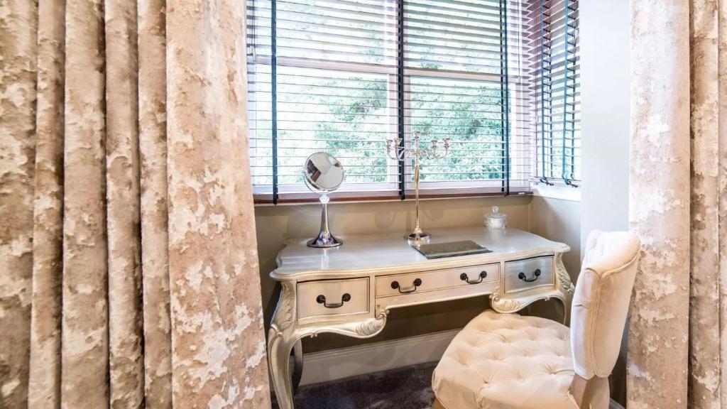 a dressing table with a mirror and a chair in a window at Derby Manor in Bournemouth