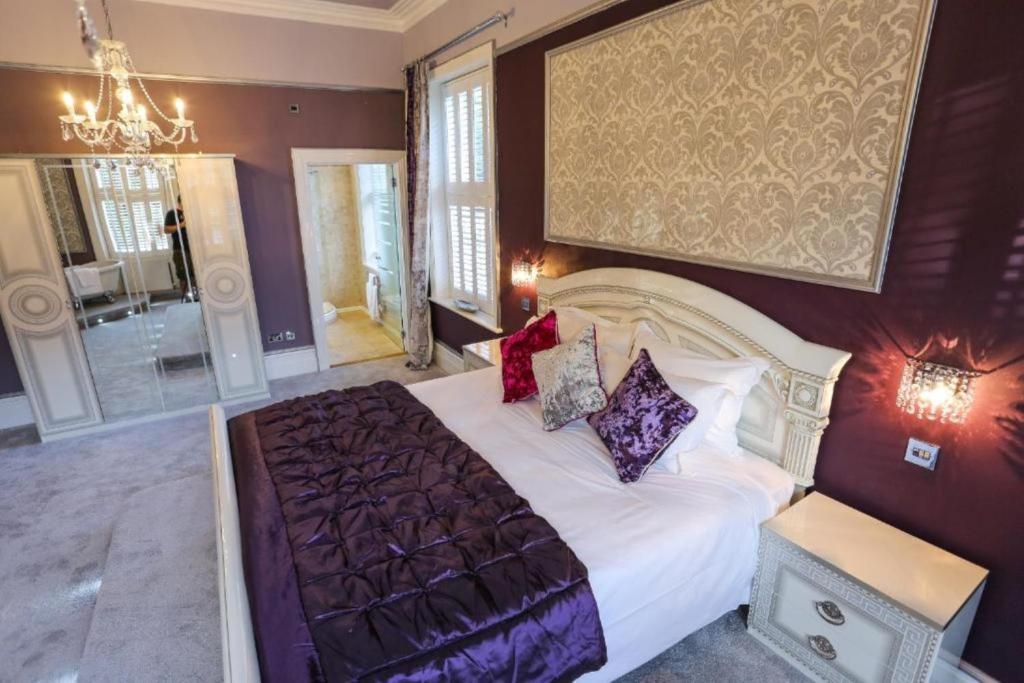 a bedroom with a large bed and a chandelier at Derby Manor in Bournemouth