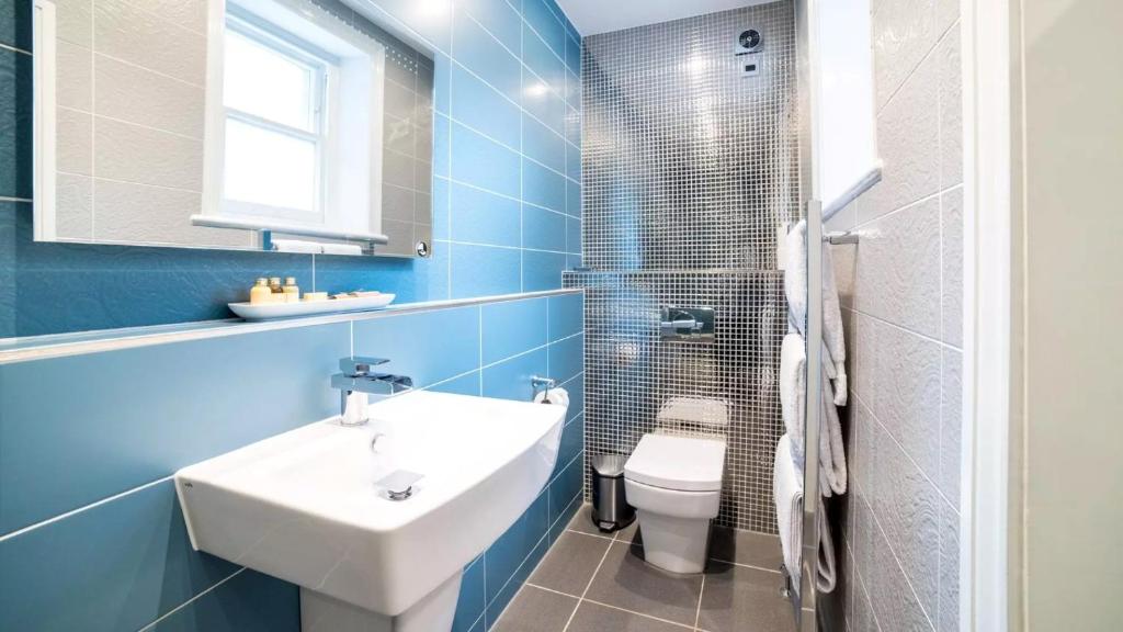 a blue bathroom with a sink and a toilet at Derby Manor in Bournemouth