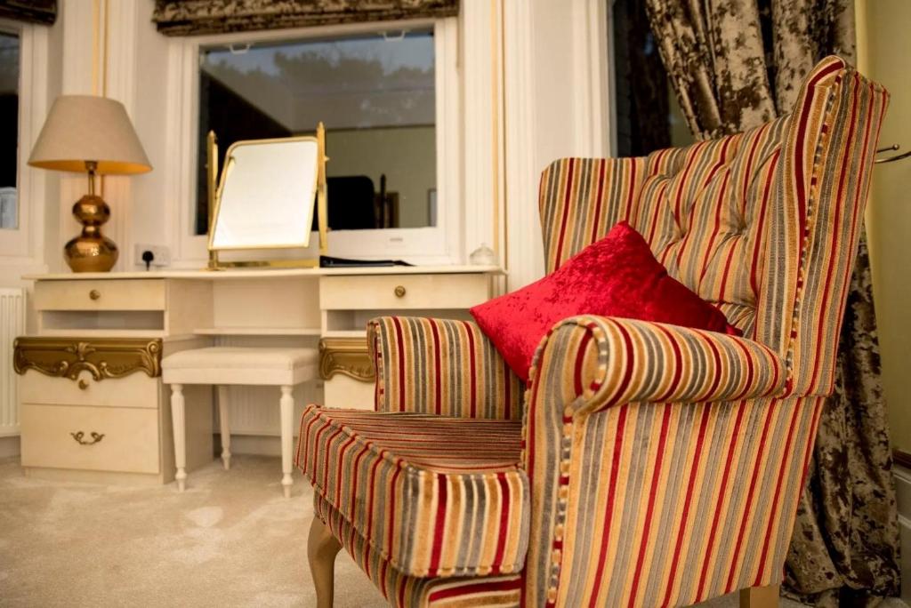 a room with a chair and a desk with a red pillow at Derby Manor in Bournemouth