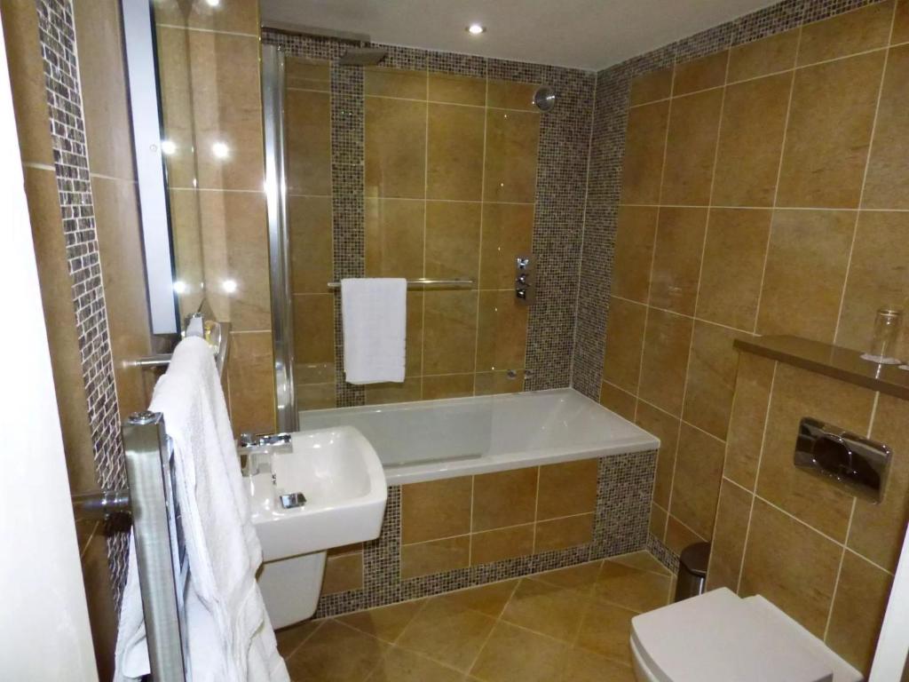 a bathroom with a tub and a sink and a toilet at Derby Manor in Bournemouth