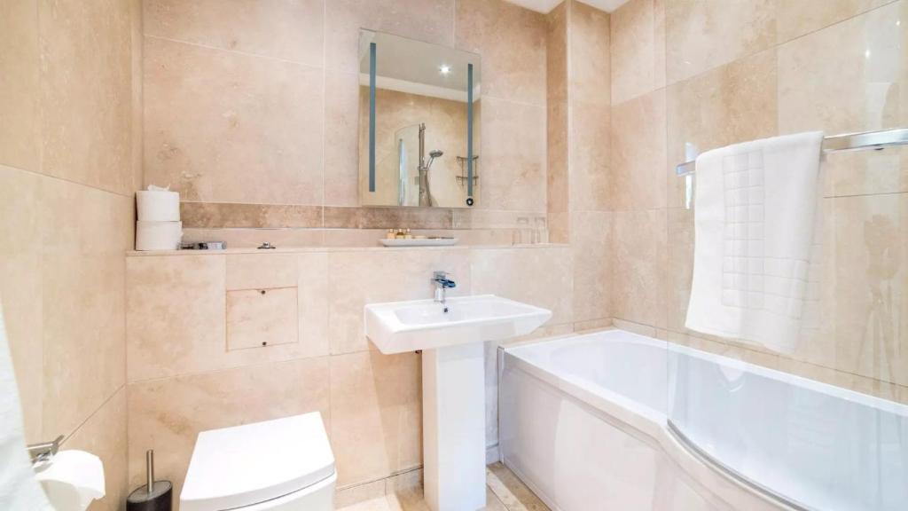 a bathroom with a sink and a tub and a toilet at Derby Manor in Bournemouth