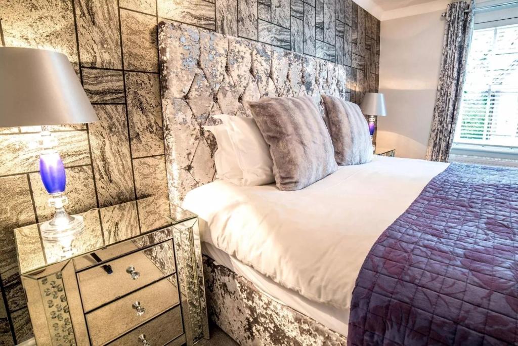 a bedroom with a king sized bed with a stone wall at Derby Manor in Bournemouth