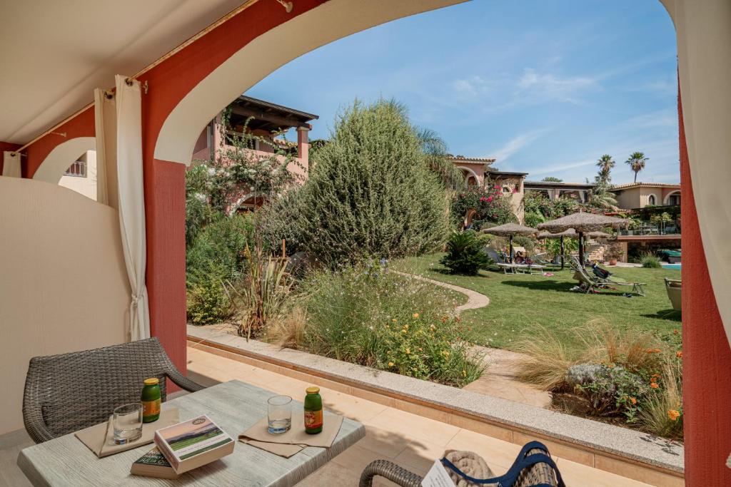 a patio with a table and a view of a garden at Hotel Mariposas in Villasimius