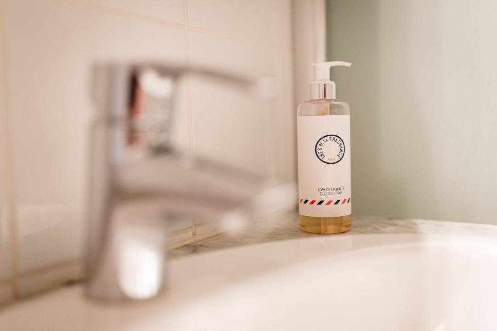 - une bouteille de savon assise à côté d'un lavabo dans l'établissement Camilla, à Tourgéville