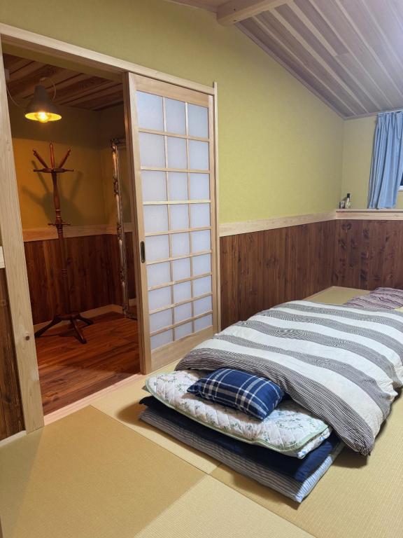 a bed in a room with a sliding glass door at まるごや 船でしか行けない離島の一棟貸し宿 in Hinase