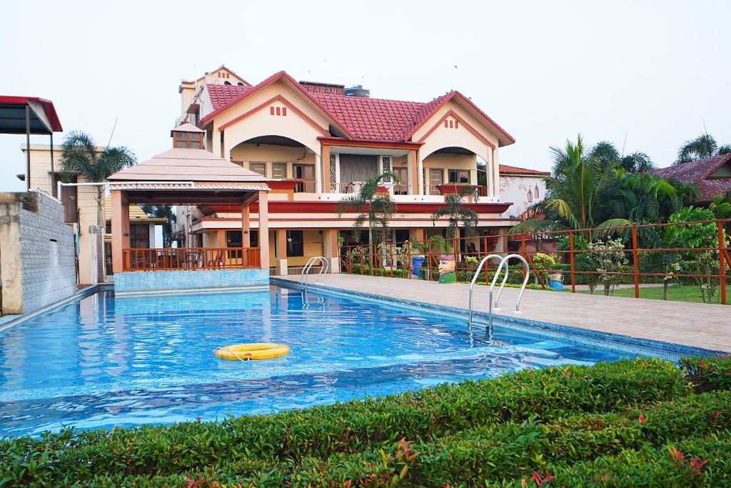 a swimming pool in front of a house at Gharana Resort , Singur !! Best Family Resort Near Kolkata with Swimming pool !! in Singur