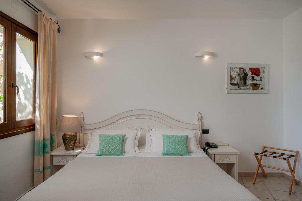 a bedroom with a large white bed with green pillows at Hotel Mariposas in Villasimius