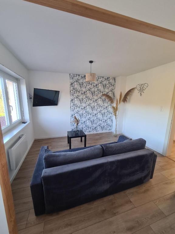 Una sala de estar con un sofá azul y una mesa. en Lumineux appartement F4, en Trois-Fontaines