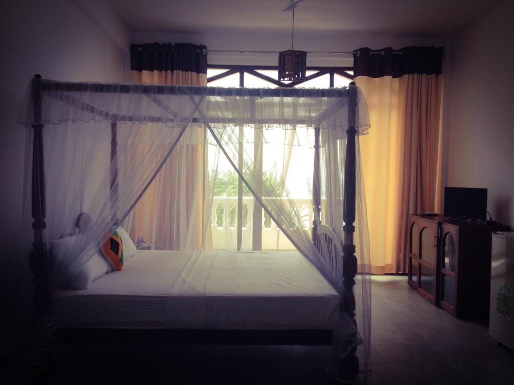 sypialnia z łóżkiem z baldachimem i oknem w obiekcie Mirissa Seastar w mieście Mirissa
