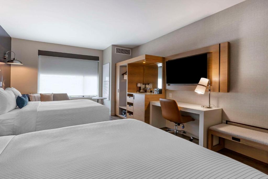 a hotel room with two beds and a desk at Cambria Hotel Austin Airport in Austin