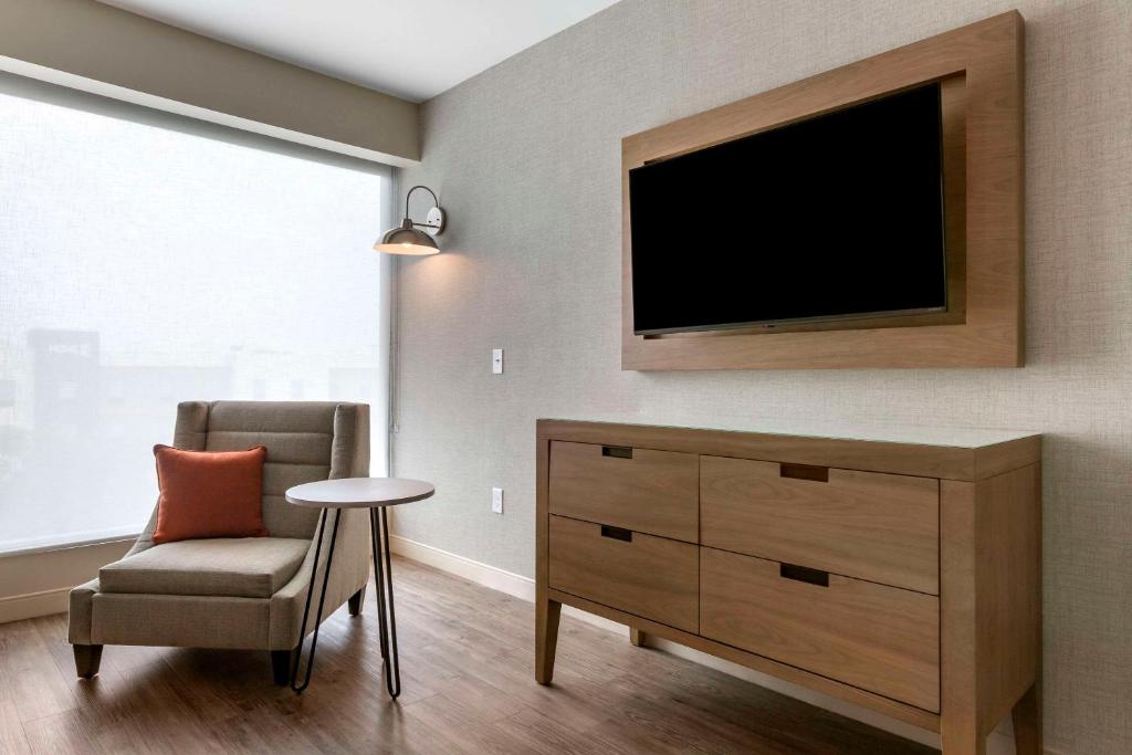 a living room with a tv and a chair at Cambria Hotel Austin Airport in Austin