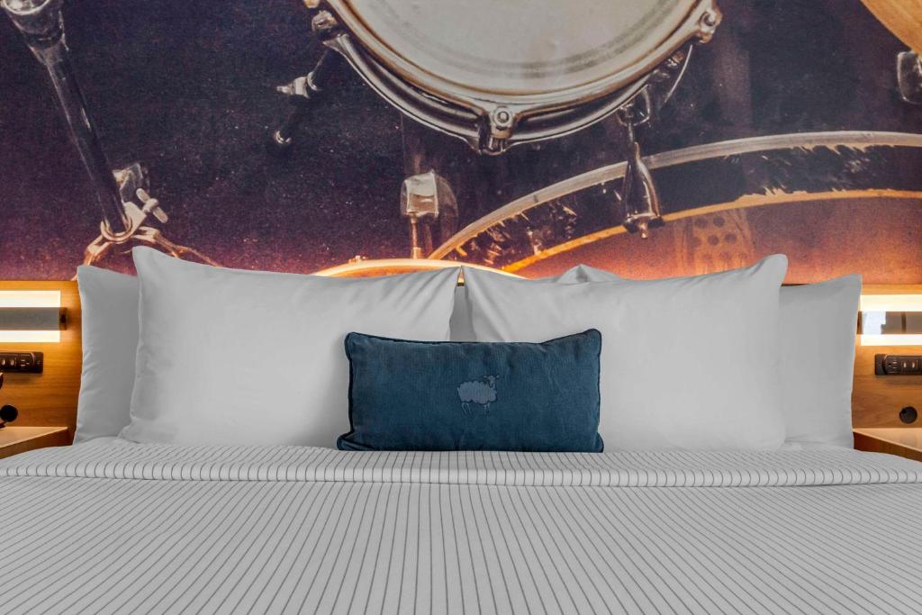 a white bed with a blue pillow on it at Cambria Hotel Austin Airport in Austin