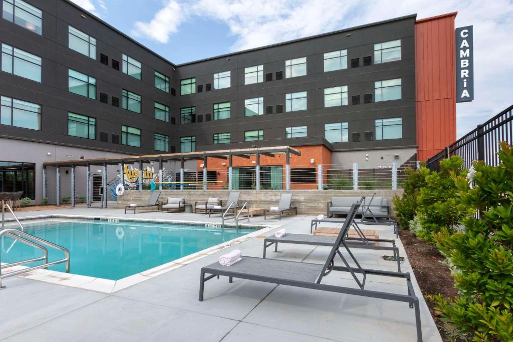 a swimming pool in front of a building at Cambria Hotel Austin Airport in Austin