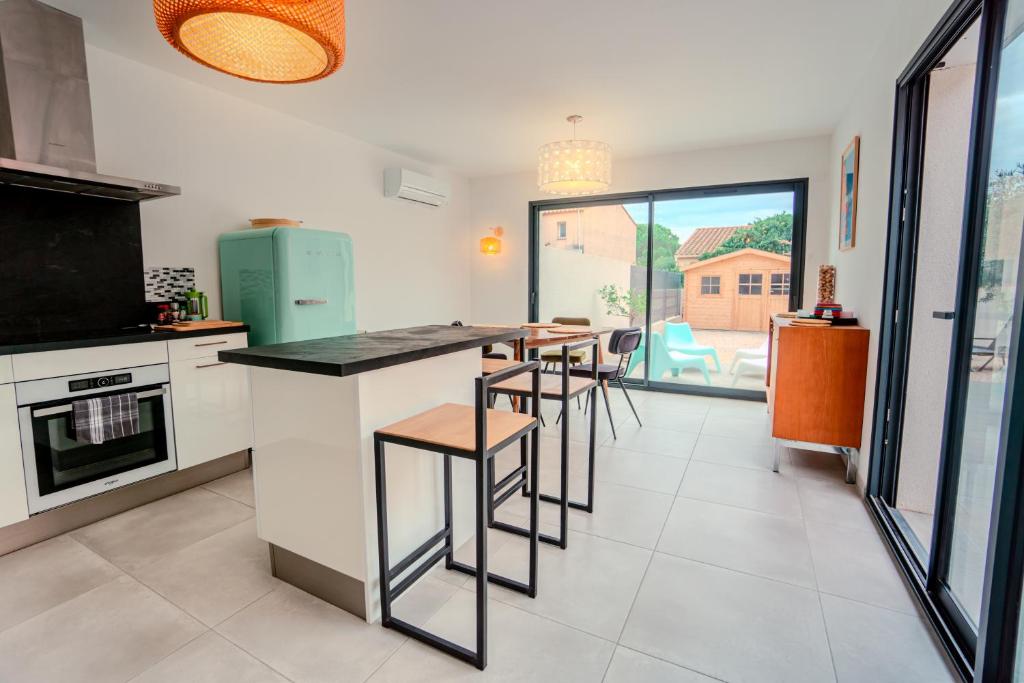 - une cuisine avec un comptoir et quelques tabourets dans l'établissement La contemporaine 2 chambres à Ste Marie, à Sainte-Marie-la-Mer