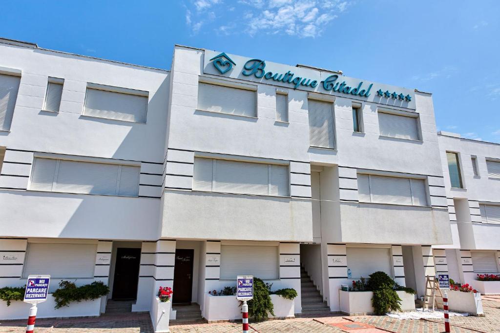 ein weißes Gebäude mit einem Schild darauf in der Unterkunft Apartamente Aparthotel Ella Boutik Cytadell in Eforie Sud