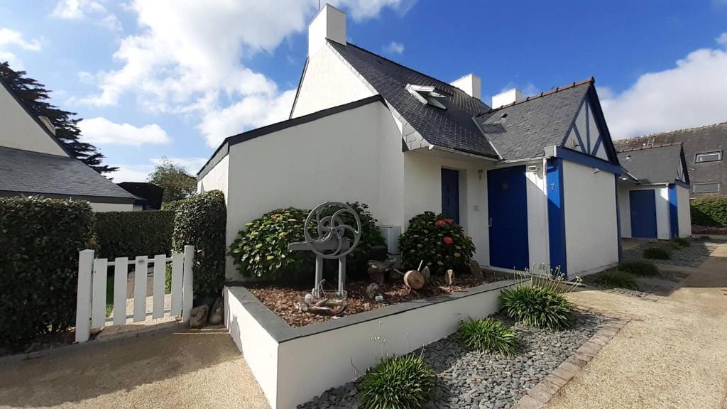 une maison blanche et bleue avec une clôture dans l'établissement Agréable maison, jardin clos, 200m plage, à La Trinité-sur-Mer