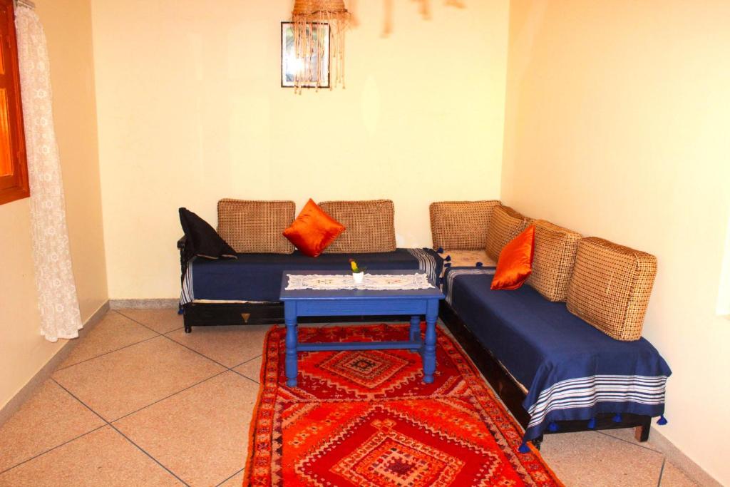 a living room with two beds and a table at Asunfou : Appartement d'apaisement in Mirleft