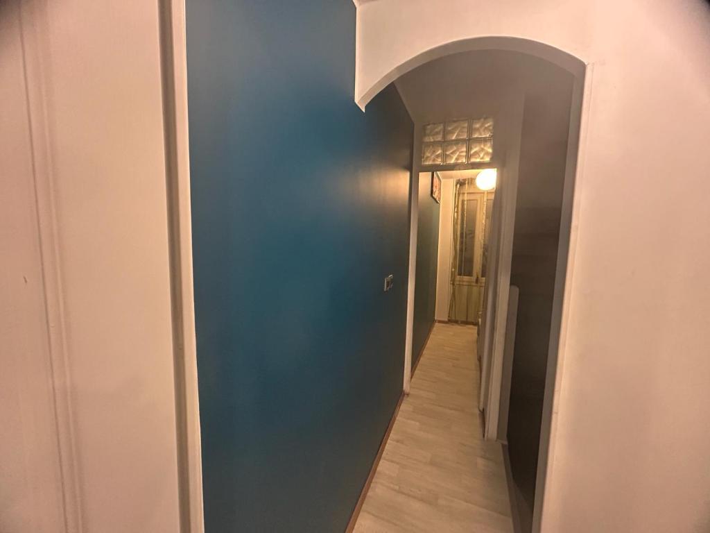 a hallway with a blue wall and a hallway leading to a door at Chambre première étage in Lille