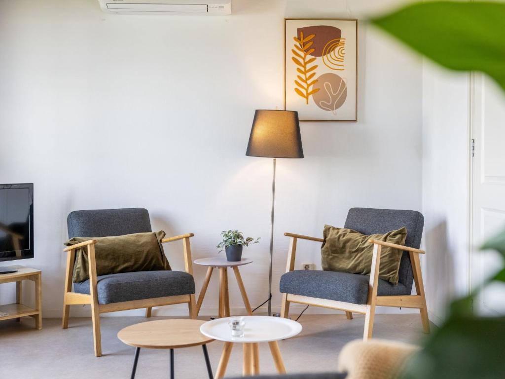 a living room with two chairs and a lamp at Holiday Home Natuurlijk de Veenhoop by Interhome in De Veenhoop